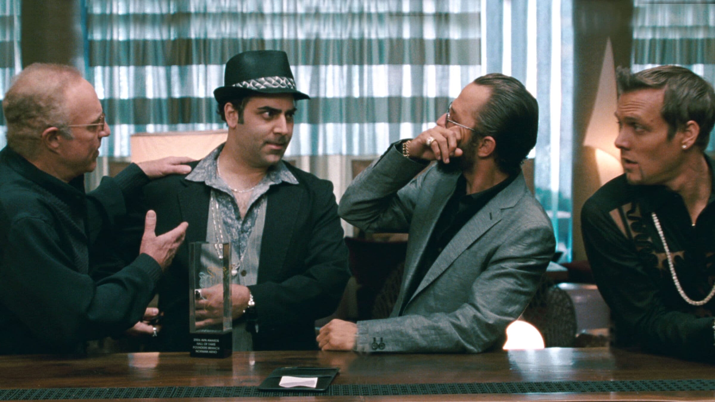 Still from the film Middle Men — four men in conversation in a lounge