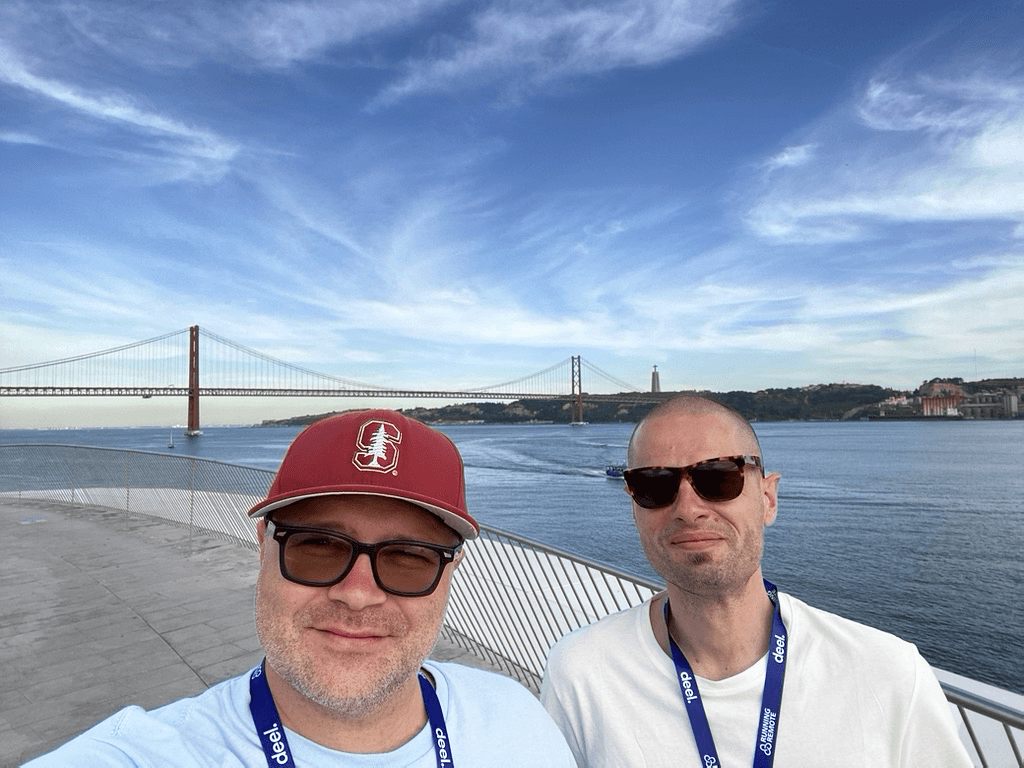 Blaze and Rob, co-founders of SEO Savages, at a waterfront with a suspension bridge in the background