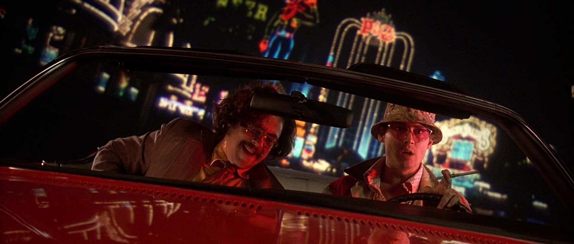 Still from Fear and Loathing in Las Vegas — two characters driving through neon-lit Las Vegas at night
