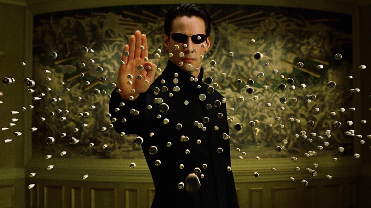 Still from The Matrix Reloaded: Neo raises one hand and stops a wall of bullets in mid-air