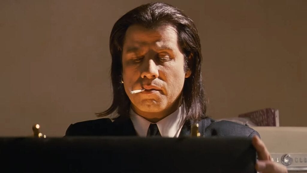 A man in a black suit opens a briefcase and its contents light his face with a golden glow