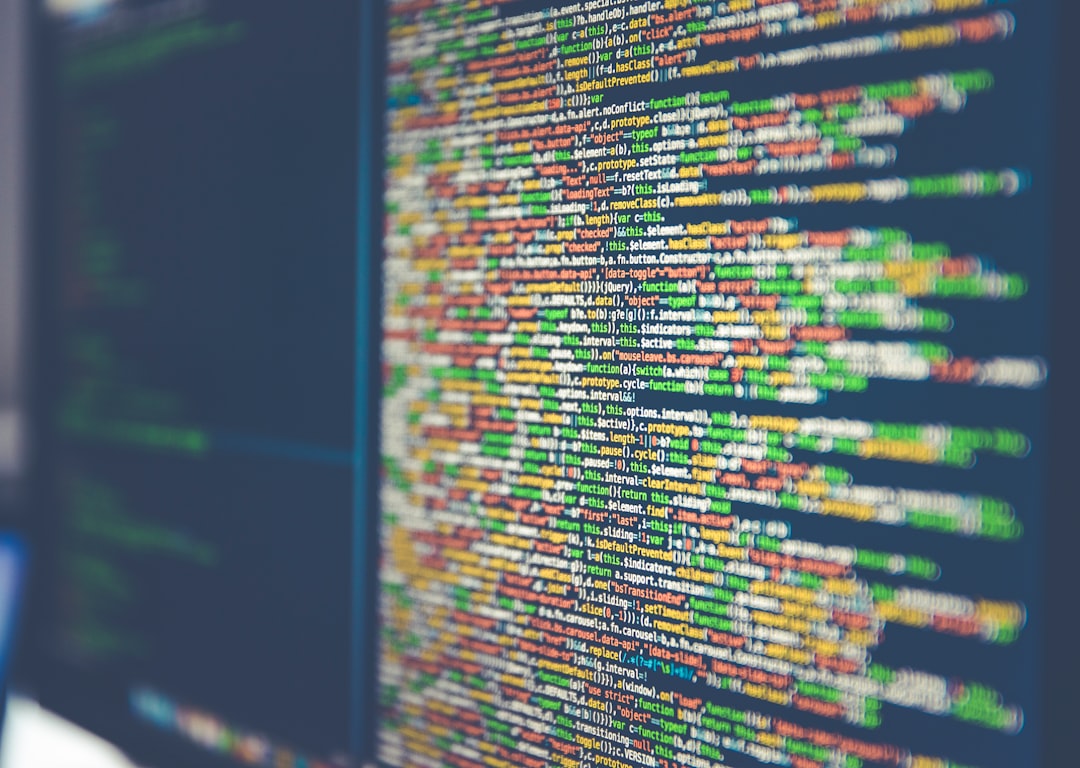 Colourful syntax-highlighted source code filling a monitor screen, shot at a shallow angle